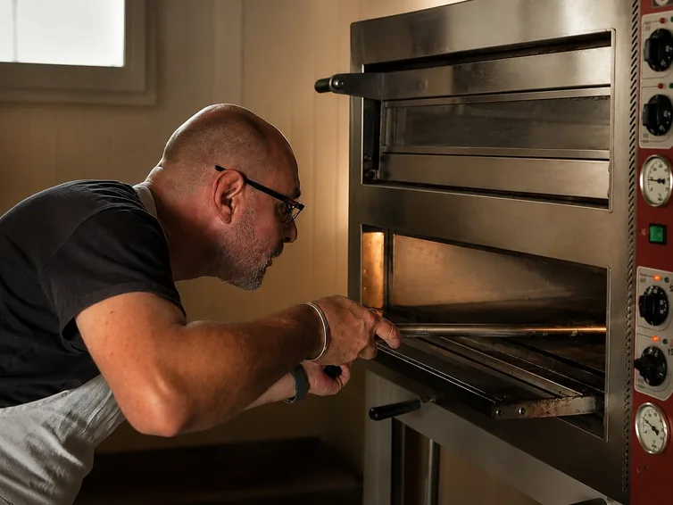 Stéphane enfourne une pizza dans le four à pizza